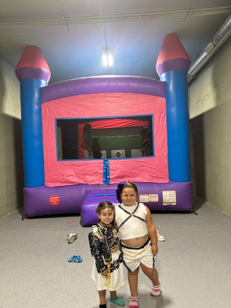 Two girls in costumes posing in front of bounce house at Malia's birthday party at ATR