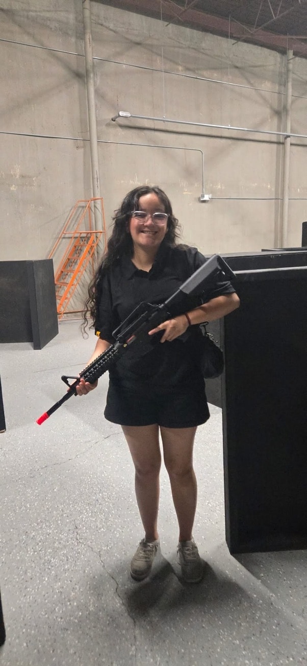 Player smiling and holding an airsoft rifle on the arena floor at ATR